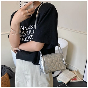 Silver quilted shoulder bag with metal studs worn by a model in an indoor setting