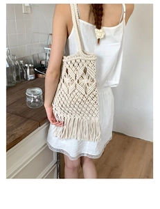 Detail of handmade cream macrame tote bag with long fringe on a female model