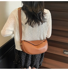 Sac demi-lune en cuir marron avec bandoulière réglable et détails métalliques dorés