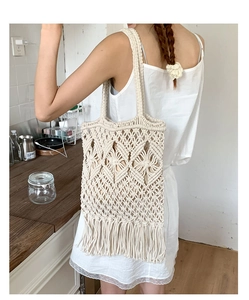 Macro shot of ivory macrame tote bag featuring woven diamond patterns and long fringe
