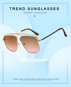Close-up of golden aviator sunglasses with brown gradient lenses and UV400 protection