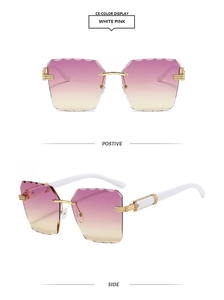 Detail view of rimless sunglasses with wavy cut pink gradient lenses and gold metal trim