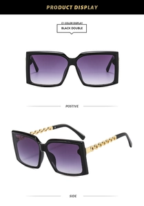Detail of square black sunglasses with purple gradient lenses and gold chain temples