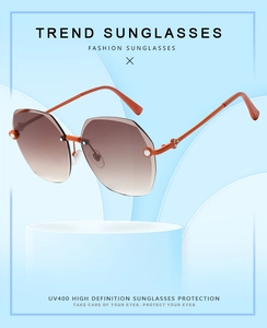 Detail of rimless sunglasses with brown gradient lenses and orange metal temples