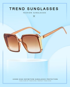 Detail of square amber sunglasses with gradient lenses and gold metal temple accents
