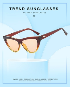 Detail of amber cat-eye sunglasses with gradient orange lenses and gold metal accents