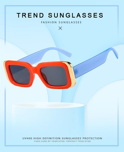Detail of red square sunglasses with gold metal corner accents and blue temples