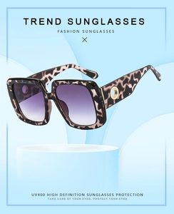 Detail of square oversized tortoiseshell sunglasses with purple gradient lenses and gold accents