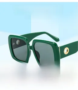 Detail of dark green square sunglasses with gold metal ring accents and grey lenses