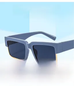 Detail of blue-grey square sunglasses with gold metal trim on a minimalist platform