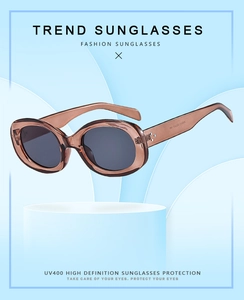Detail view of oval tea-colored sunglasses with UV400 protection on a blue pedestal