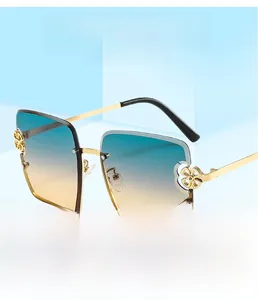 Détail de lunettes de soleil carrées avec verres dégradés bleu-jaune et fleurs dorées