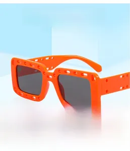 Detail of bright orange square sunglasses featuring unique geometric hollow-out frame design