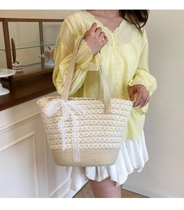 Detail of hand-woven straw tote with exquisite lace trim and a decorative white bow
