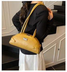 Detail of yellow crocodile pattern baguette bag with silver metallic buckle accents
