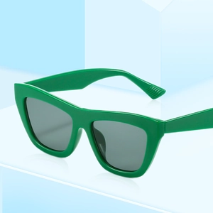 Fashionable green cat-eye sunglasses with dark grey lenses on a blue geometric background
