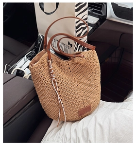 Detail of hand-woven straw tote bag with brown leather strap on luxury car seat