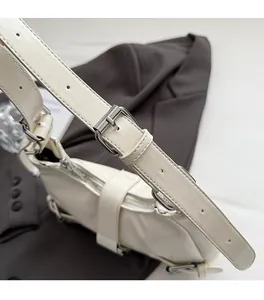 Detailed close-up of adjustable silver buckle and metal rings on a white shoulder bag