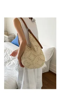 Detail of cream crochet bag featuring hollow-out floral pattern and brown leather strap