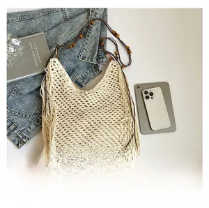 Détail du sac de plage au crochet avec franges et perles en bois sur fond de jean