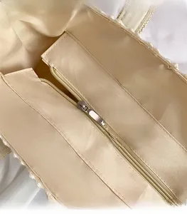 Close-up of high-quality metal zipper and smooth inner lining on lace woven beach bag
