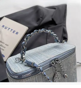 Detail of light blue tweed bag with floral pendant and woven chain handle
