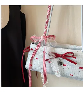 Dettaglio della borsa in tessuto bianco con fiocchi rossi e manico in pizzo decorativo