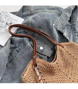 Detail of hand-woven tote bag with brown leather straps and metallic ring connectors