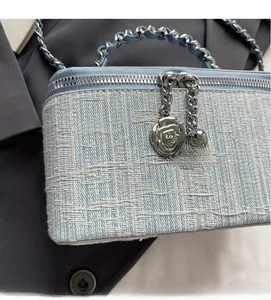 Detail of light blue tweed box bag with silver rose pendant and woven chain strap
