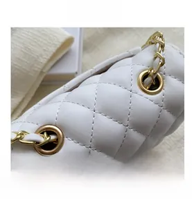 Macro shot of white quilted leather bag detailing with light gold chain and grommet hardware