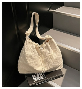 Detailed shot of pleated canvas tote with drawstring and textured waffle fabric on stairs