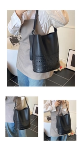 Detailed view of black laser-cut hollow bucket bag with adjustable shoulder strap
