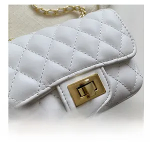 Detail of the white quilted leather texture and golden metal rotary lock on the mini bag