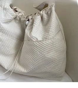 Detail of beige checkered seersucker tote bag showing textured fabric and drawstring