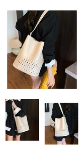 Detail of cream bucket bag with laser-cut geometric patterns and wavy edge stitching