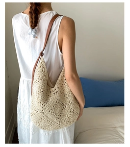 Detail of hand-crocheted sunflower patterns on beige cotton shoulder bag with leather strap