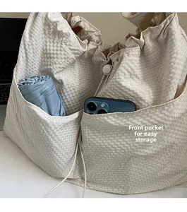 Detail view of large drawstring nylon tote bag showing front pockets with phone and umbrella