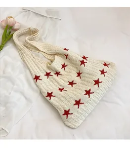 Dettaglio della borsa tote in maglia crema con stelle rosse e trama all'uncinetto