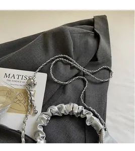 Detail of silver pleated bag featuring a metallic chain strap and ball adjustment buckle