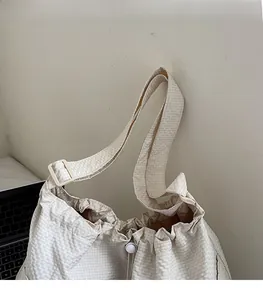 Detail of checkered tote bag showing adjustable shoulder strap and drawstring closure