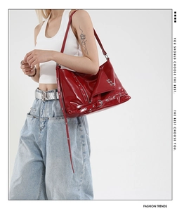 Close-up of bright red patent leather tote bag with punk style metal rings and zippers