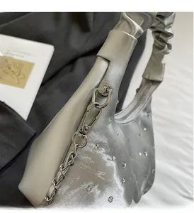 Close-up of silver pleated dumpling bag with rhinestones and metal chain handle