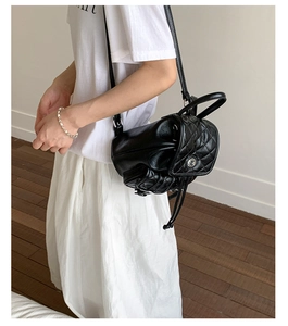 Detail of black quilted leather backpack with silver rotating clasp and drawstring sides