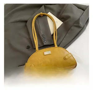 Detail shot of bright yellow crocodile embossed handbag on a grey suit jacket background