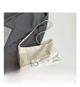 Dettaglio della borsa punk bianca con fibbie metalliche su sfondo abito grigio