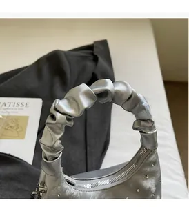 Detail of silver metallic handbag with sparkling rhinestones and ruffled cloud-style handle