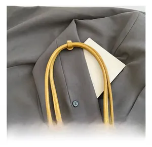 Detail view of the yellow leather bag featuring a round handle and a leather strap buckle