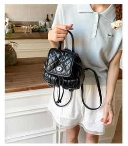 Detailed view of a black quilted leather backpack with silver clasp and drawstring closure