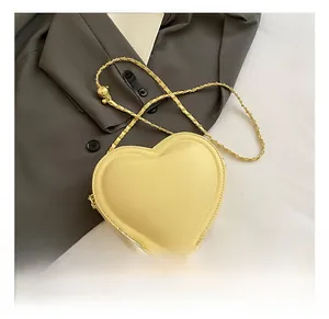 Détail du sac à bandoulière en cuir jaune clair en forme de cœur avec chaîne dorée