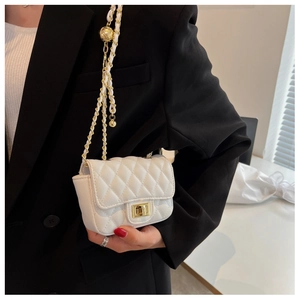 Detail of white quilted crossbody bag featuring a gold clasp and metal chain strap